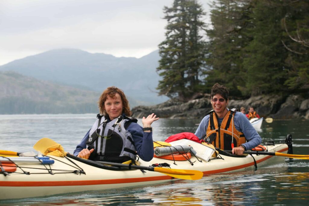 Kayaking Couple | Sea Quest Kayak Tours An advenurous couple kayaking in Alaska waves to you.