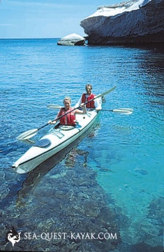 Arroyo-Blanco-Lg-235x360 | Sea Quest Kayak Tours Two people kayaking on clear, blue water near a rocky coastline.