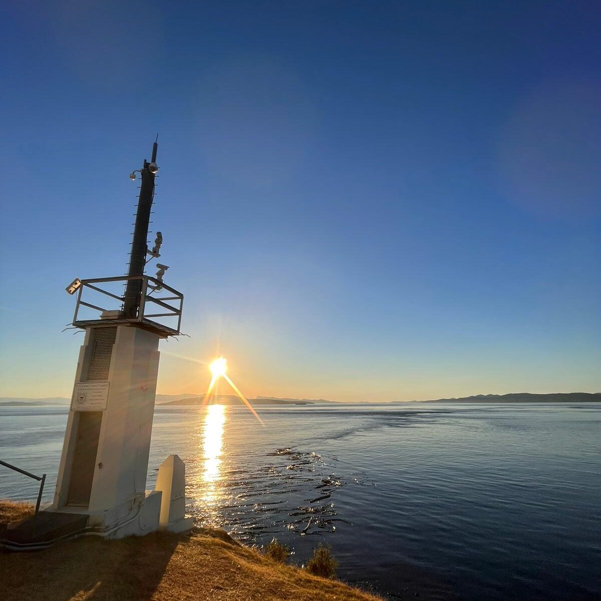 san-juan-island-national-monument-edited.jpg | Sea Quest Kayak Tours A view of the ocean at sunset with the sun low on the horizon as seen from the deck of a boat with part of the boats structure visible in the foreground